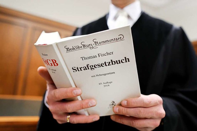 Ein Richter hlt das Strafgesetzbuch in der Hand (Symbolbild).  | Foto: Oliver Berg (dpa)