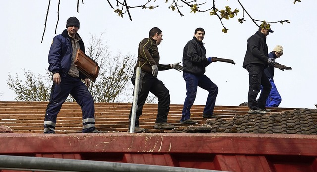 Feuerwehrleute entfernen die alten Ziegel vom Dach des Gemeindezentrums.  | Foto: Roland Vitt
