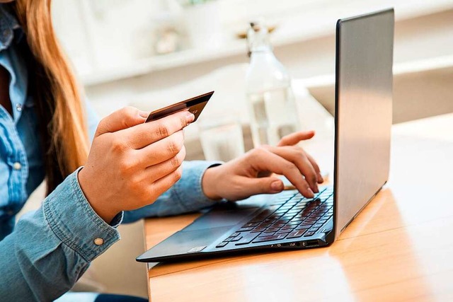 Eine Frau tippt die Nummer ihrer Kreditkarte in ein Laptop.  | Foto: Christin Klose (dpa)