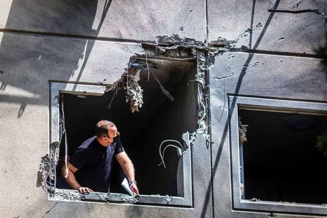 Ein Mann inspiziert die Schden an ein...n abgefeuerten Rakete getroffen wurde.  | Foto: Ilia Yefimovich (dpa)