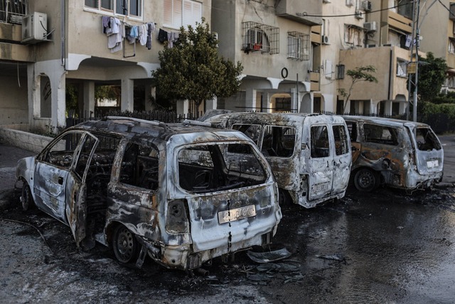 Verbrannte Fahrzeuge sind nach Unruhen in der Stadt Lod zu sehen.  | Foto: Ilia Yefimovich (dpa)