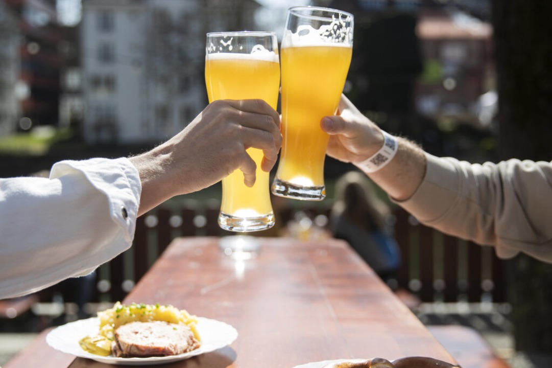 Wieder mglich: Zwei Menschen sitzen b...ergarten und stoen mit einem Bier an.  | Foto: Tom Weller (dpa)
