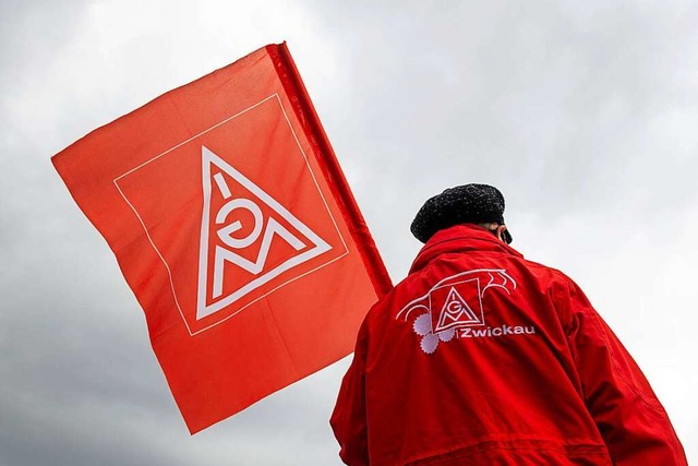 Ein Mitglied der Gewerkschaft IG Metall schwenkt eine Fahne.  | Foto: Hendrik Schmidt (dpa)