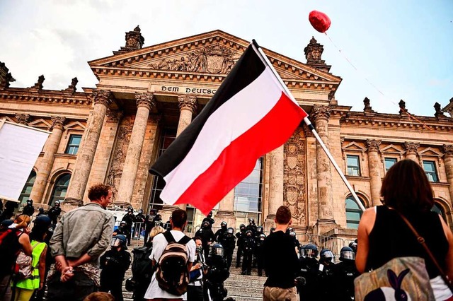 Ein Demonstrant schwenkt vor dem Berliner Reichstag die Reichsflagge.  | Foto: Fabian Sommer (dpa)