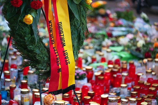 Trauerkerzen und Blumen  liegen vor einem Kaufhaus in der Innenstadt.  | Foto: Nicolas Armer (dpa)