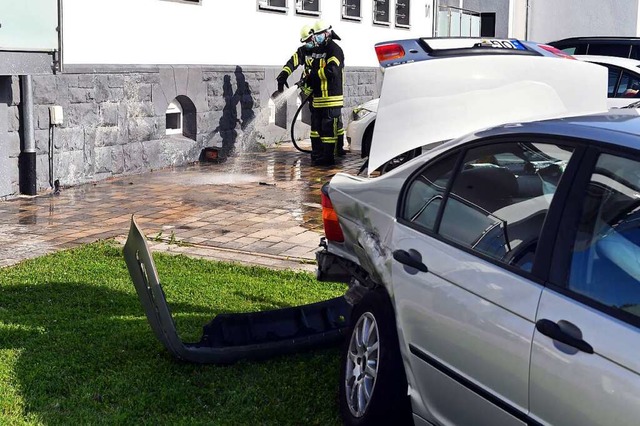 Feuerwehrleute reinigen die Hauswand, ...rie des Unfallwagens bespritzt wurde.   | Foto: Wolfgang Knstle