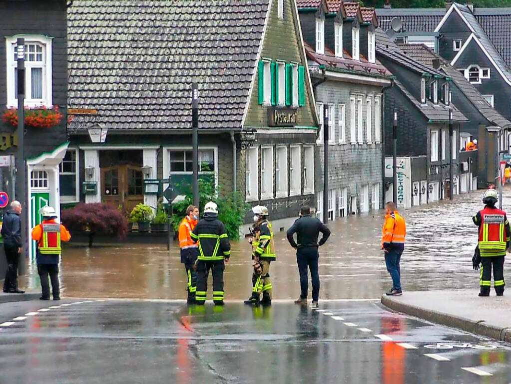 Einsatzkrfte stehen an einer berschwemmten Strae in Solingen.