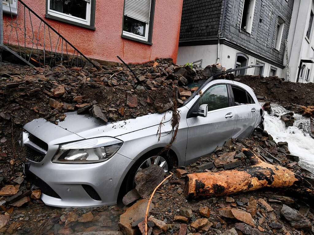 Ein Auto ist in Hagen vom Schutt bedeckt, den die berflutung der Nahmerbach am Vorabend mit sich gebracht hat.