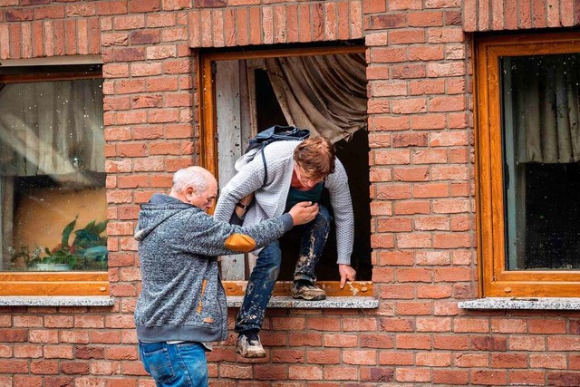 Ein Mann hilft einer Frau aus dem Fenster.  | Foto: BERND LAUTER (AFP)