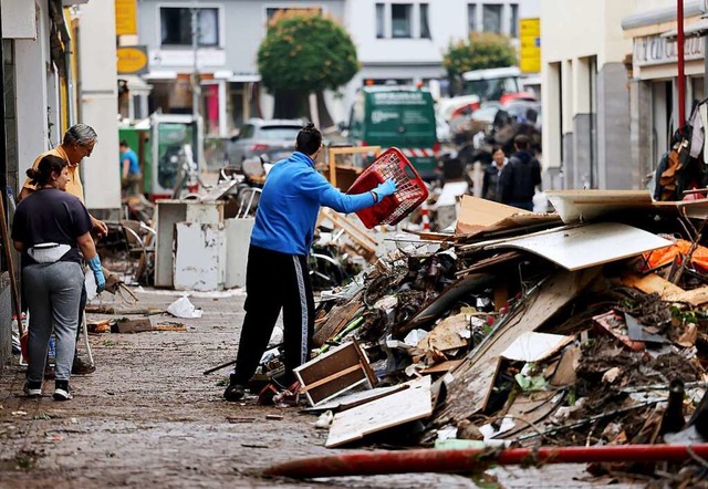 Menschen rumen in der Fugngerzone v...m die Urft ber die Ufer getreten war.  | Foto: Oliver Berg (dpa)