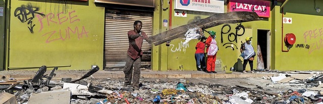 Ein Mann hilft vor einem verwsteten E...rban, Trmmer und Mll zu beseitigen.   | Foto: GUILLEM SARTORIO (AFP)