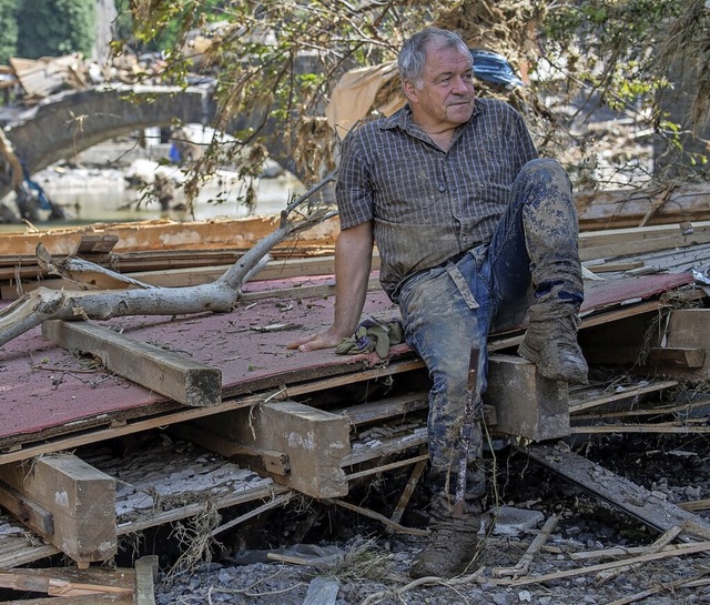 Ein Helfer ruht sich auf Treibgut und Trmmern aus.  | Foto: Boris Roessler (dpa)