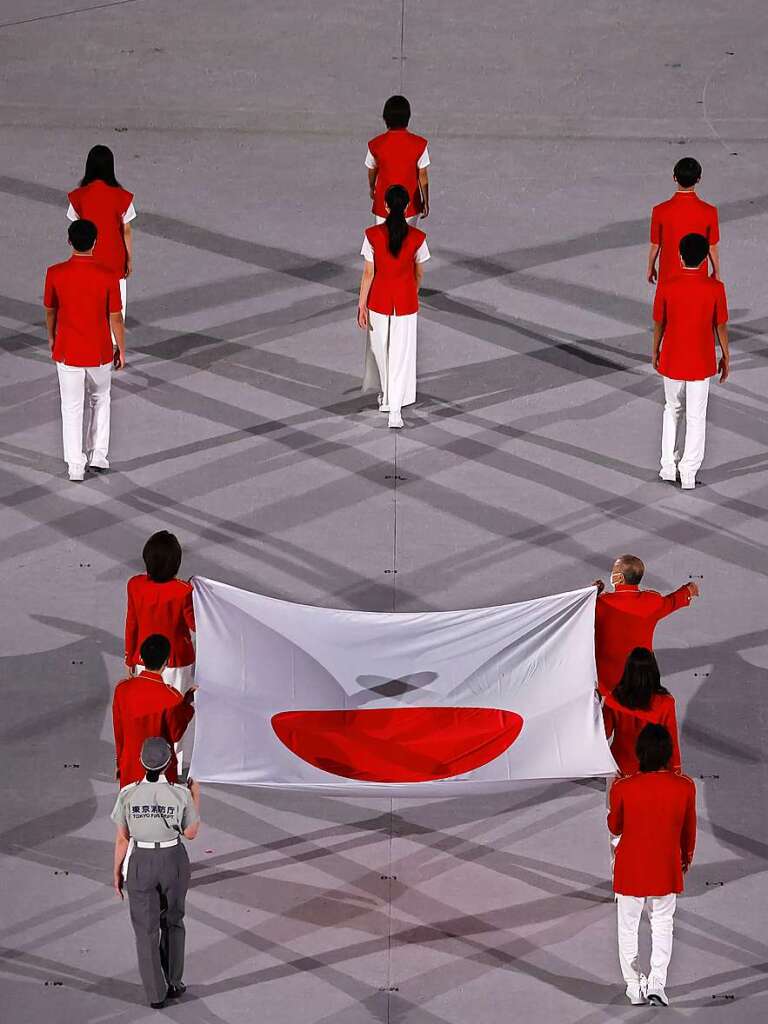 Die japanische Flagge wird ins Stadion gebracht, unter anderem von der ehemaligen Olympiasiegerin Takahashi Naoko, die 2000 in Sydney Gold im Marathon holte.