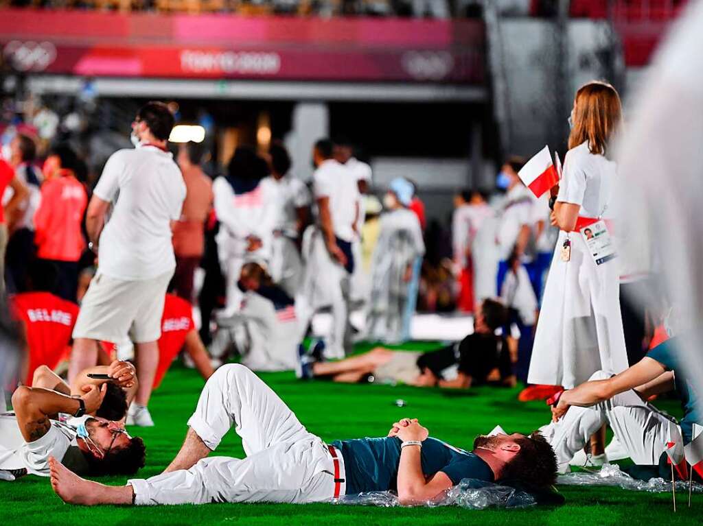 Athletinnen und Athleten verfolgen die Schlusszeremonie entspannt liegend im Olympiastadion von Tokio.