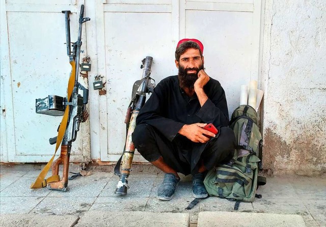 Ein Taliban-Kmpfer sitzt am Mittwoch im afghanischen Farah neben seinen Waffen.  | Foto: Mohammad Asif Khan (dpa)