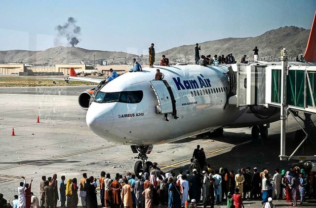 Menschen drngen in die wenigen Flugze...d klammern sich auch auen daran fest.  | Foto: WAKIL KOHSAR (AFP)