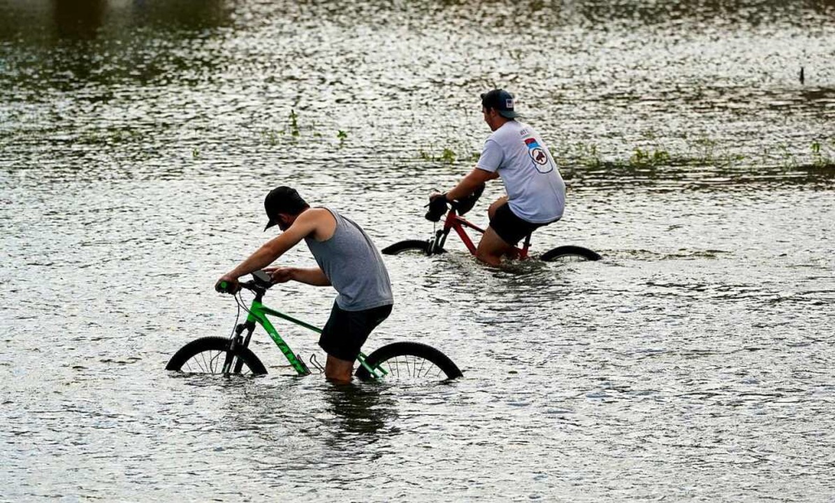 Radfahrer radeln durch die Überschwemm... Nähe des Yachthafens von New Orleans.  | Foto: Eric Gay (dpa)