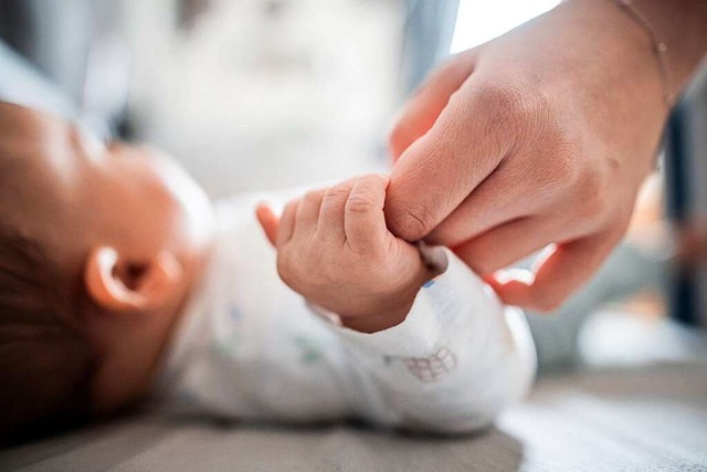 Ein Baby hlt den Finger seiner Mutter fest.  | Foto: Fabian Strauch (dpa)