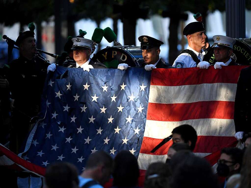 New Yorker Polizisten und Feuerwehrleute halten whrend einer Gedenkveranstaltung am National September 11 Memorial and Museum eine US-Flagge hoch.