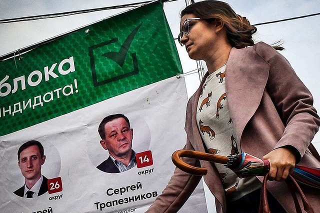 Eine Frau luft in Tomsk an Plakaten der liberalen Jabloko-Partei vorbei.  | Foto: ALEXANDER NEMENOV
