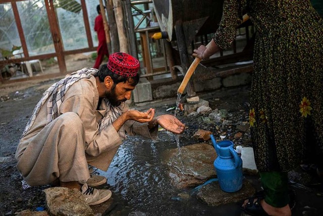 Ein afghanischer Binnenflchtling trin...em Schlauch  in einem Lager in Kabul.   | Foto: Bernat Armangue (dpa)