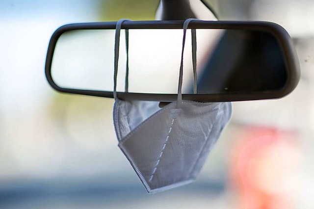 Eine FFP2-Maske hngt am Rckspiegel eines Autos.  | Foto: Daniel Karmann (dpa)