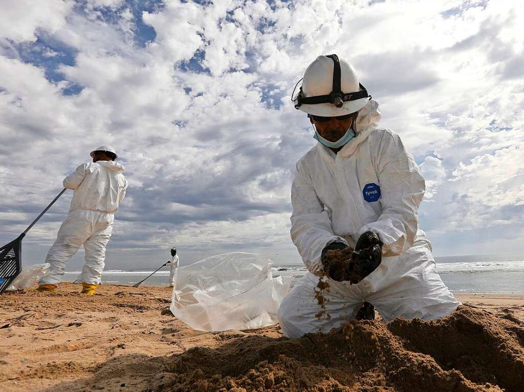 Mitglieder des Aufrumteams sammeln am Huntington Beach in Orange County, Kalifornien, l aus dem Sand.