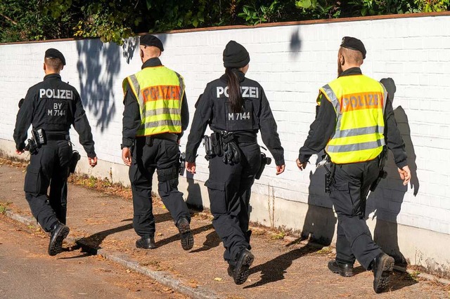 Polizisten gehen im Mnchner Stadtbezirk Bogenhausen auf einer Strae entlang.  | Foto: Peter Kneffel (dpa)