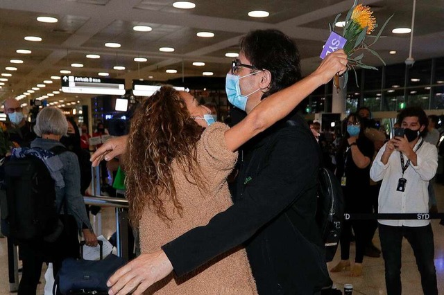 Eine Frau (l) wird von ihrem Bruder um...m Flughafen von Sydney angekommen ist.  | Foto: Rick Rycroft (dpa)