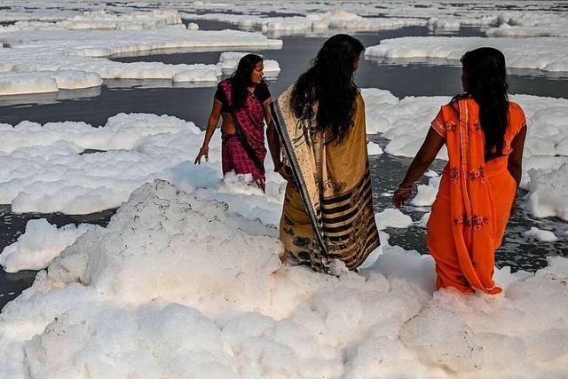 Hindus nehmen Schaumbad in einem giftigen Fluss