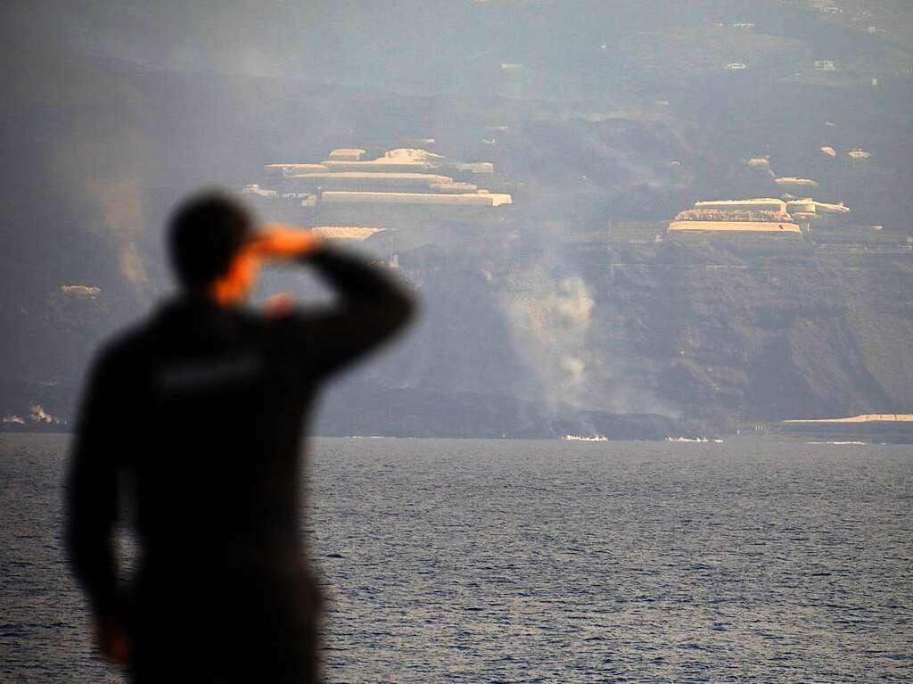 Ein Mann beobachtet, wie die Lava ins Meer fllt.