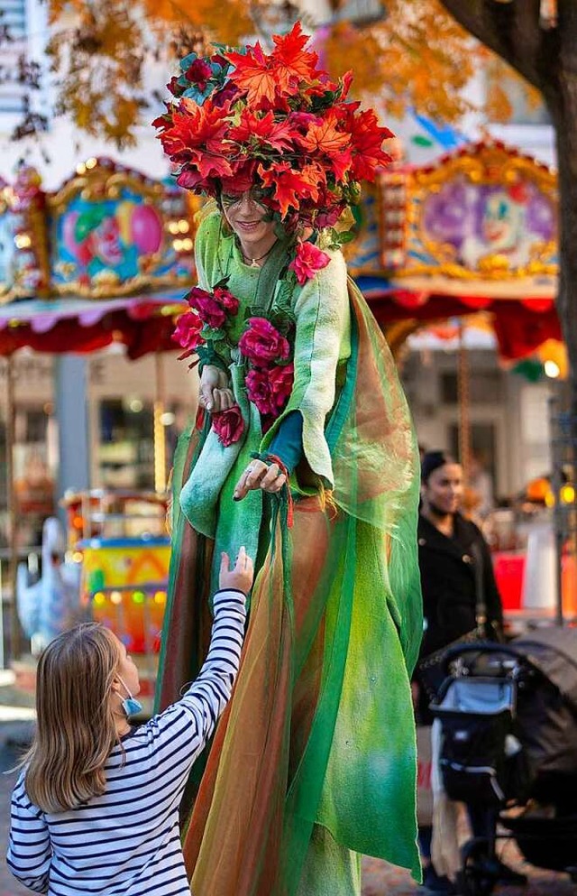 Eine Stelzenluferin brachte auf ihre Art Chrysanthemen auf den Wochenmarkt.  | Foto: Ronald Buck