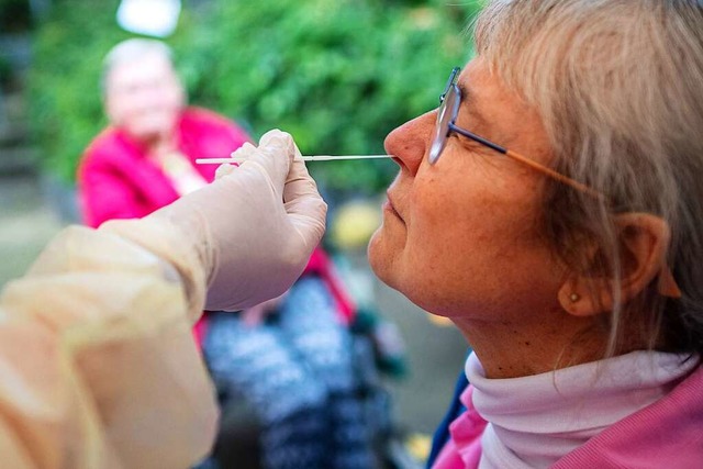 Die Mitarbeiterin eines Seniorenheims lsst sich auf das Coronavirus berprfen.  | Foto: Sina Schuldt (dpa)