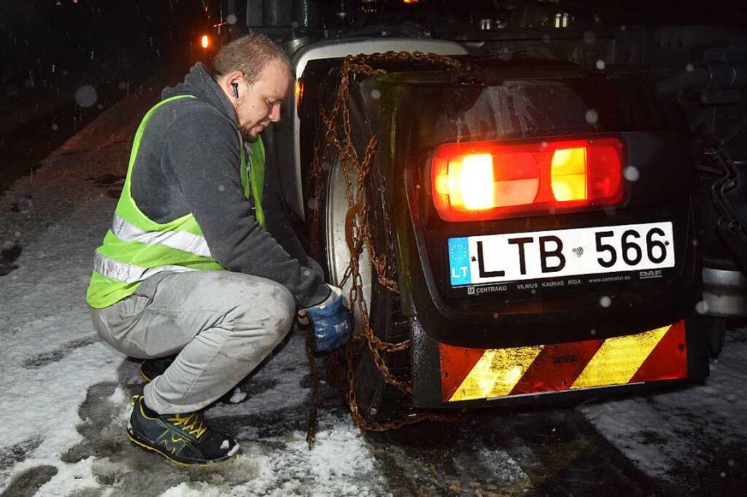 Im Höllental zieht ein Fahrer an den R...elassenen Lastwagens Schneeketten auf.  | Foto: kamera24