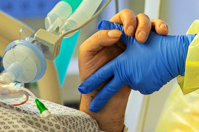 Eine Krankenschwester hlt die Hand ei...vid-Patienten auf der Intensivstation.  | Foto: Thomas Banneyer