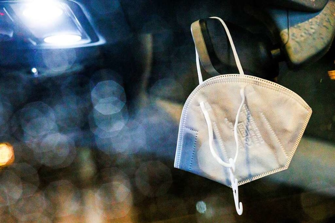 Eine FFP2-Maske hängt am Innenspiegel eines Autos.  | Foto: Philipp von Ditfurth (dpa)