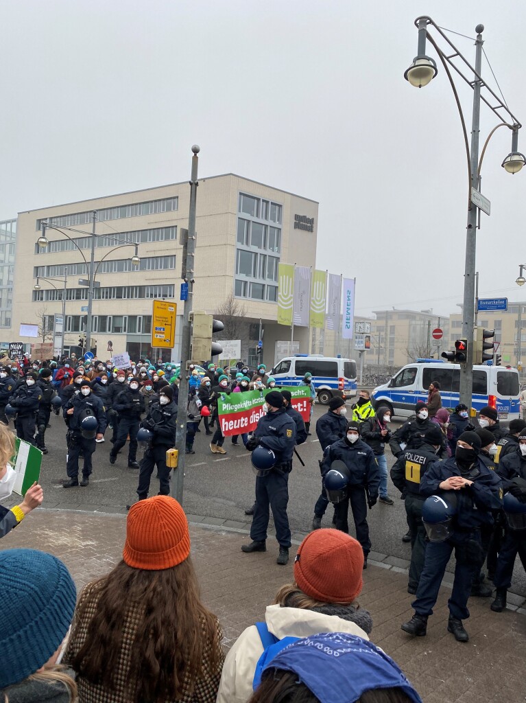 Der Demonstrationszug der Grupe „Freisein“ zieht ber die Bismarckallee. Am Rande stehen Demonstranten der vorigen Kundgebung „Querdenken“.