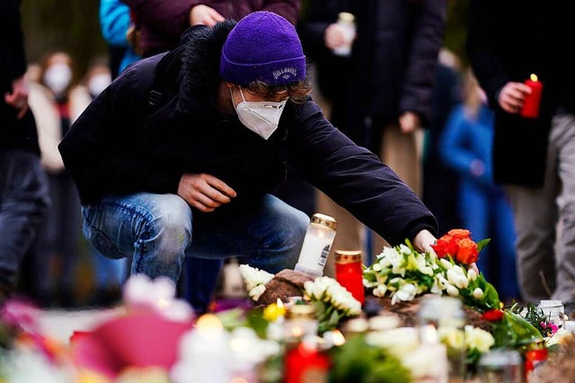 Menschen legen vor einem Gebude der U...t Blumen und Kerzen an den Wegesrand.  | Foto: Uwe Anspach (dpa)