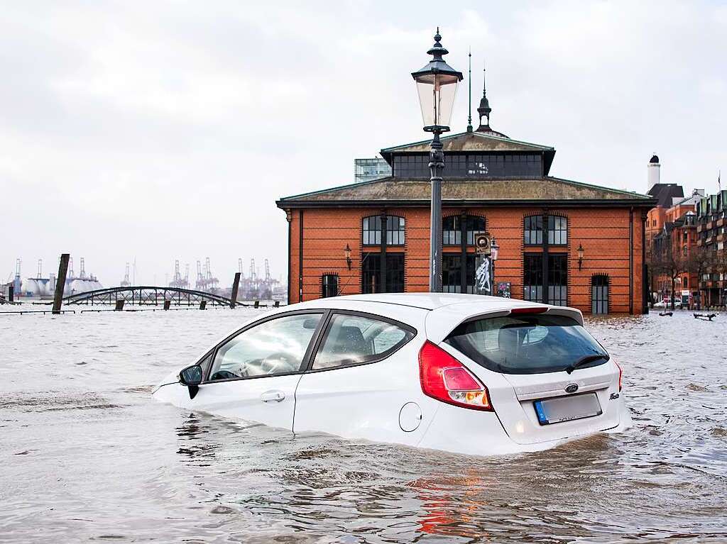 Ein Auto steht auf dem Fischmarkt mit der Fischauktionshalle whrend einer Sturmflut im Wasser der Elbe.