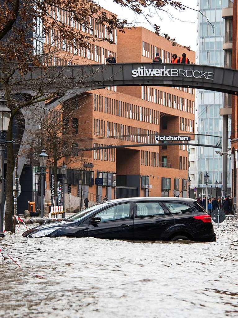 Ein Auto steht auf dem Fischmarkt mit der Fischauktionshalle whrend einer Sturmflut im Wasser der Elbe.