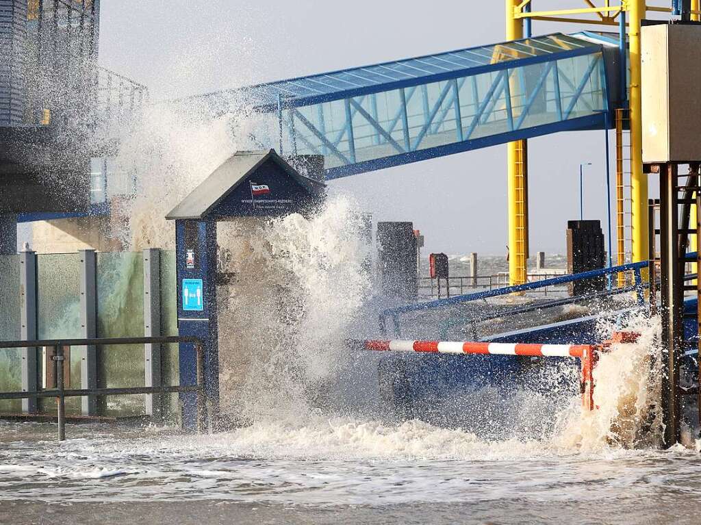 Die Gischt der aufgepeitschten Nordsee berflutet bei Sturm den Fhranleger Dagebll.