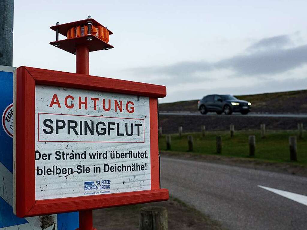 Ein Schild an einem Deich weist auf eine bevorstehende Springflut hin.