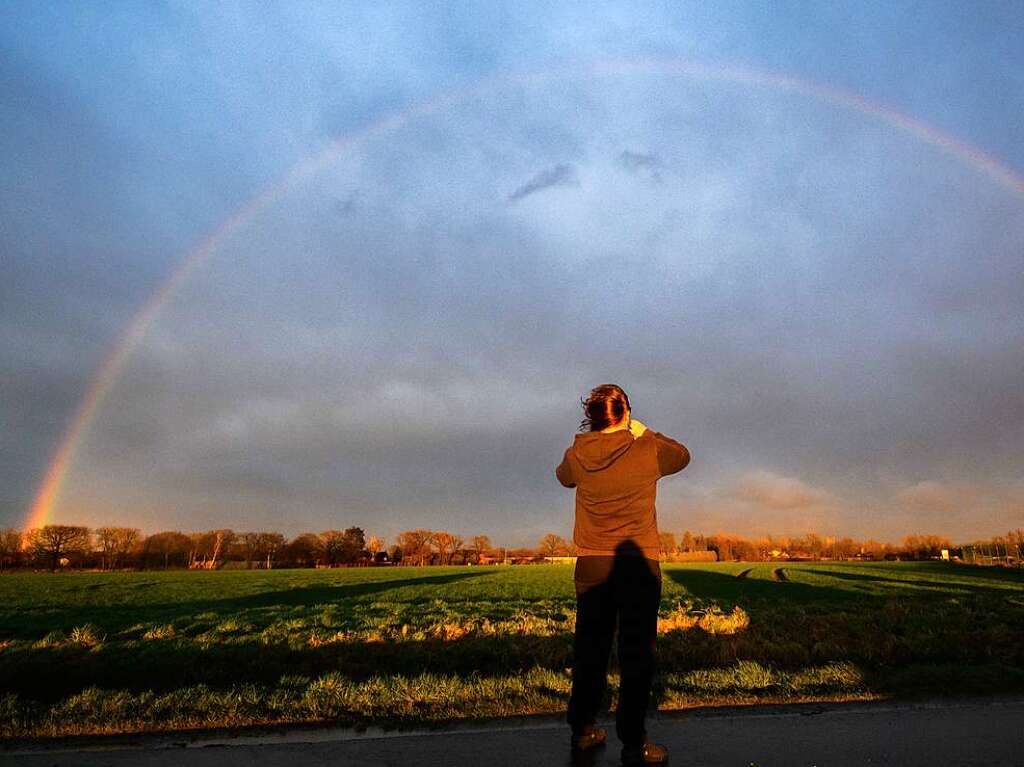 Eine Frau fotografiert whrend Orkantief Zeynep einen Regenbogen in der Region Hannover.