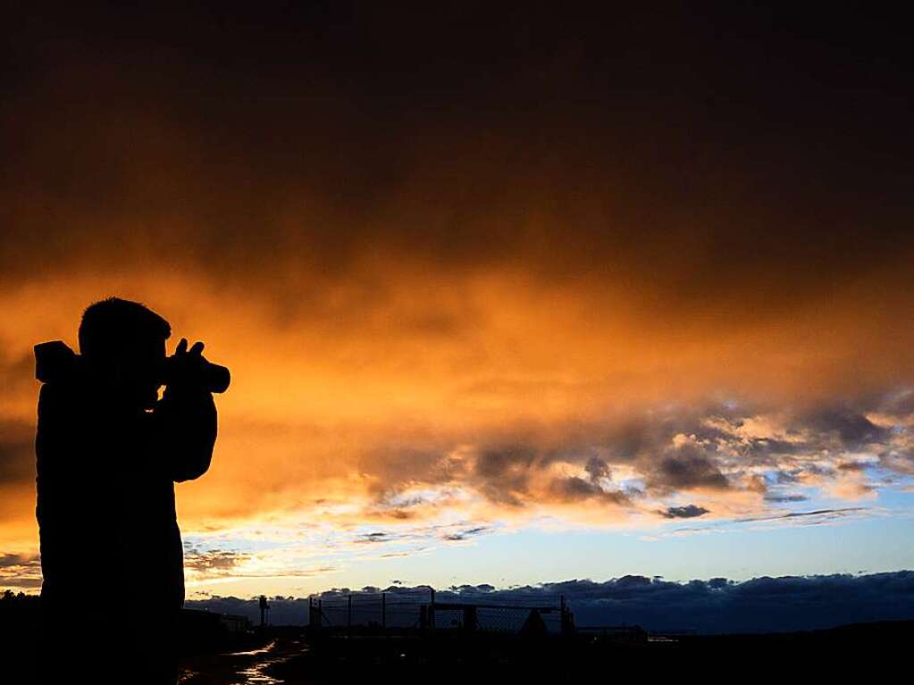 Ein Mann fotografiert whrend Orkantief Zeynep eine bedrohliche Wolkenkulisse die von der untergehenden Sonne rtlich angestrahlt wird.