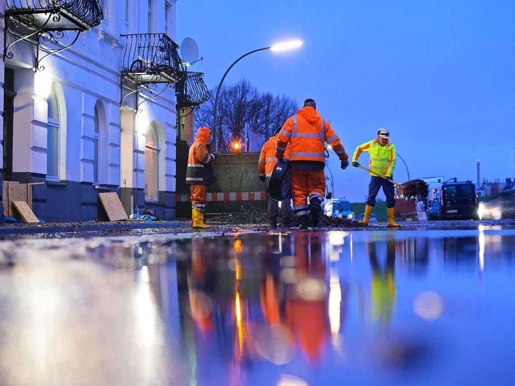 Hamburg: Mitglieder einer Polder-Gemeinschaft reinigen am frhen Morgen eine zuvor bersplte Strae auerhalb des Deiches in Wilhelmsburg.