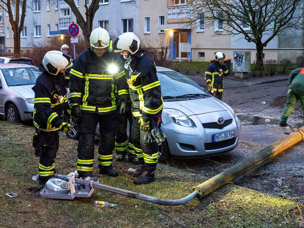 Einsatzkrfte der Freiwilligen Feuerwehr rumen eine umgestrzte Straenlaterne von der Strae.