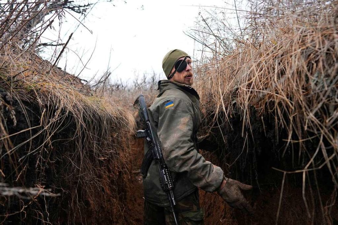 Ein ukrainischer Soldat spricht mit se... in der Nähe von Zolote einen Grabens.  | Foto: Evgeniy Maloletka (dpa)