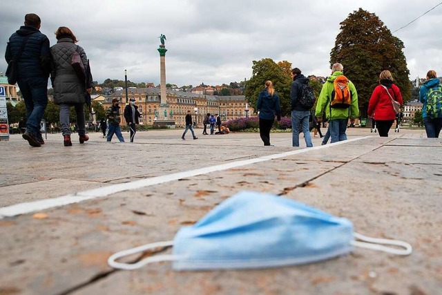 Passanten in Stuttgart gehen ber den ...Boden eine Mund-Nasen-Bedeckung liegt.  | Foto: Tom Weller (dpa)