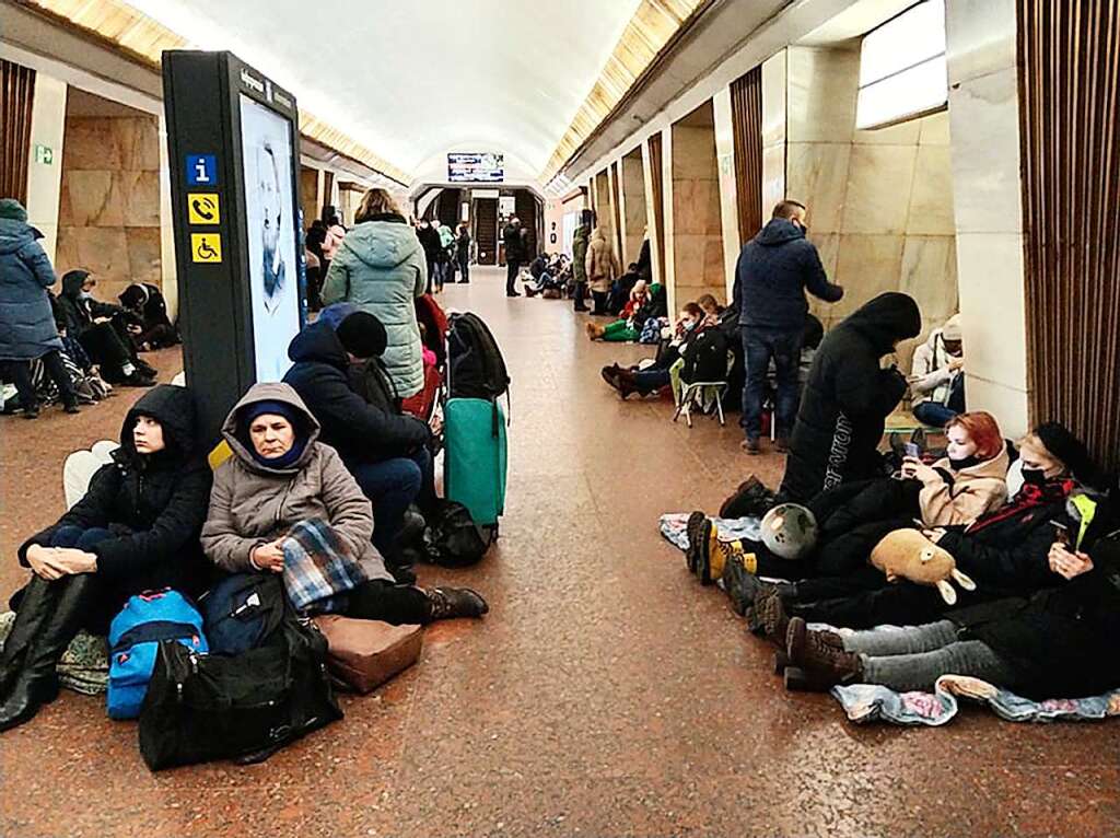 Menschen sitzen in einer U-Bahn-Station und nutzen diese als Bombenschutzraum.