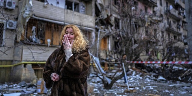 Eine Frau in Kiew am Freitag vor einem...sischen Streitkrften zerbombten Haus   | Foto: Emilio Morenatti (dpa)